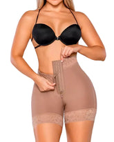 Woman wearing a black bra and beige shapewear on a plain background